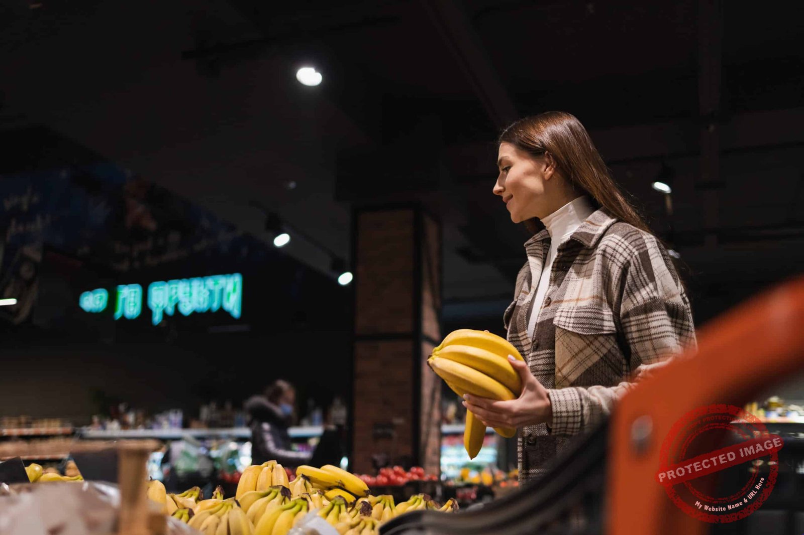 Girl buys bananas in the fruit section of the supermarket
