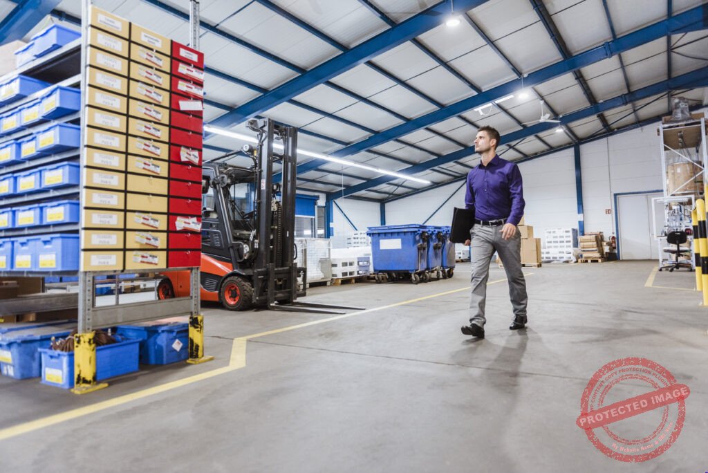 Businessman walking through shop floor, holding files