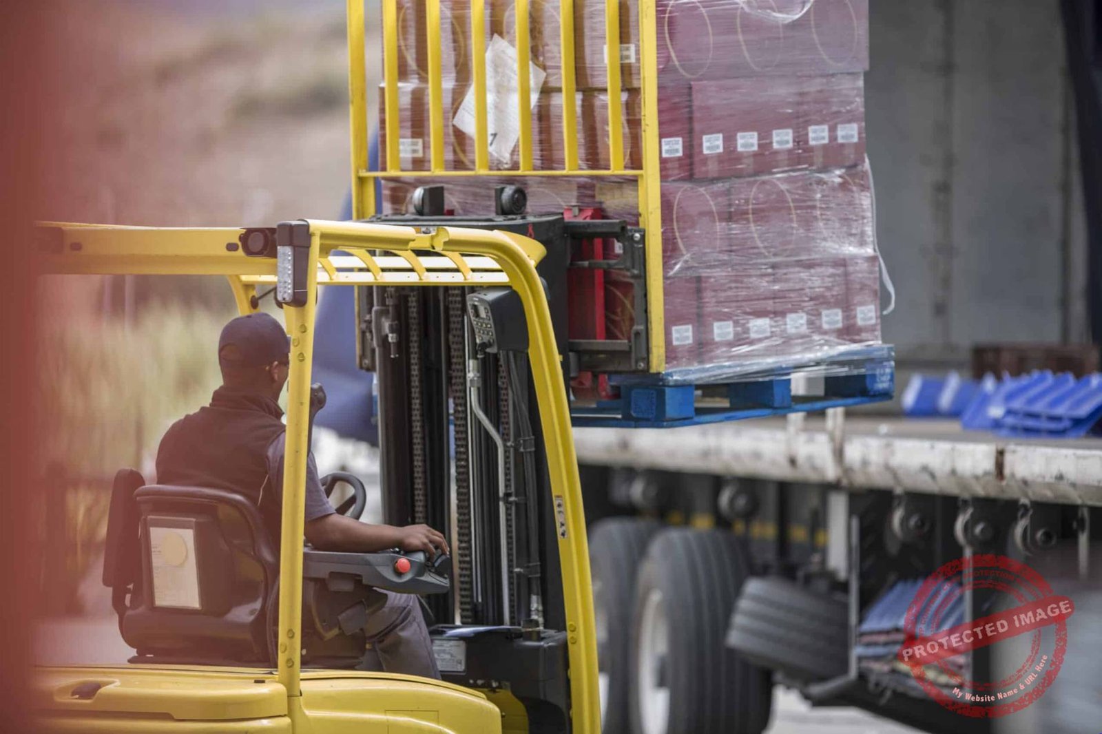 Forklift driver loading pallet onto truck at packaging factory
